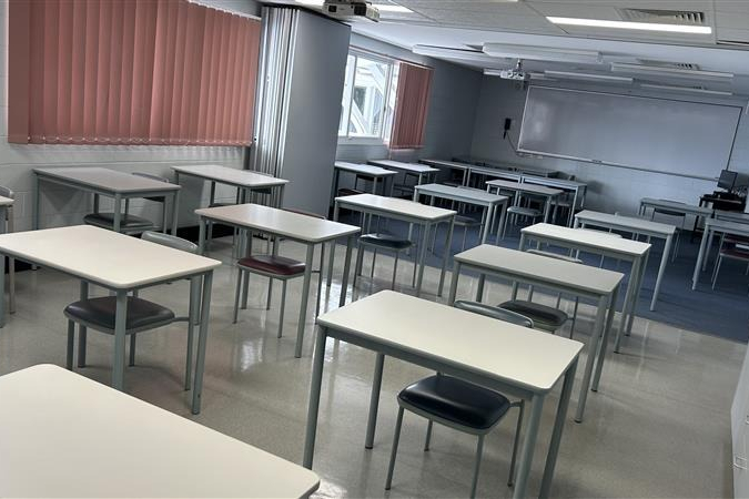 Classroom contains rows of individual desks and chairs arranged neatly