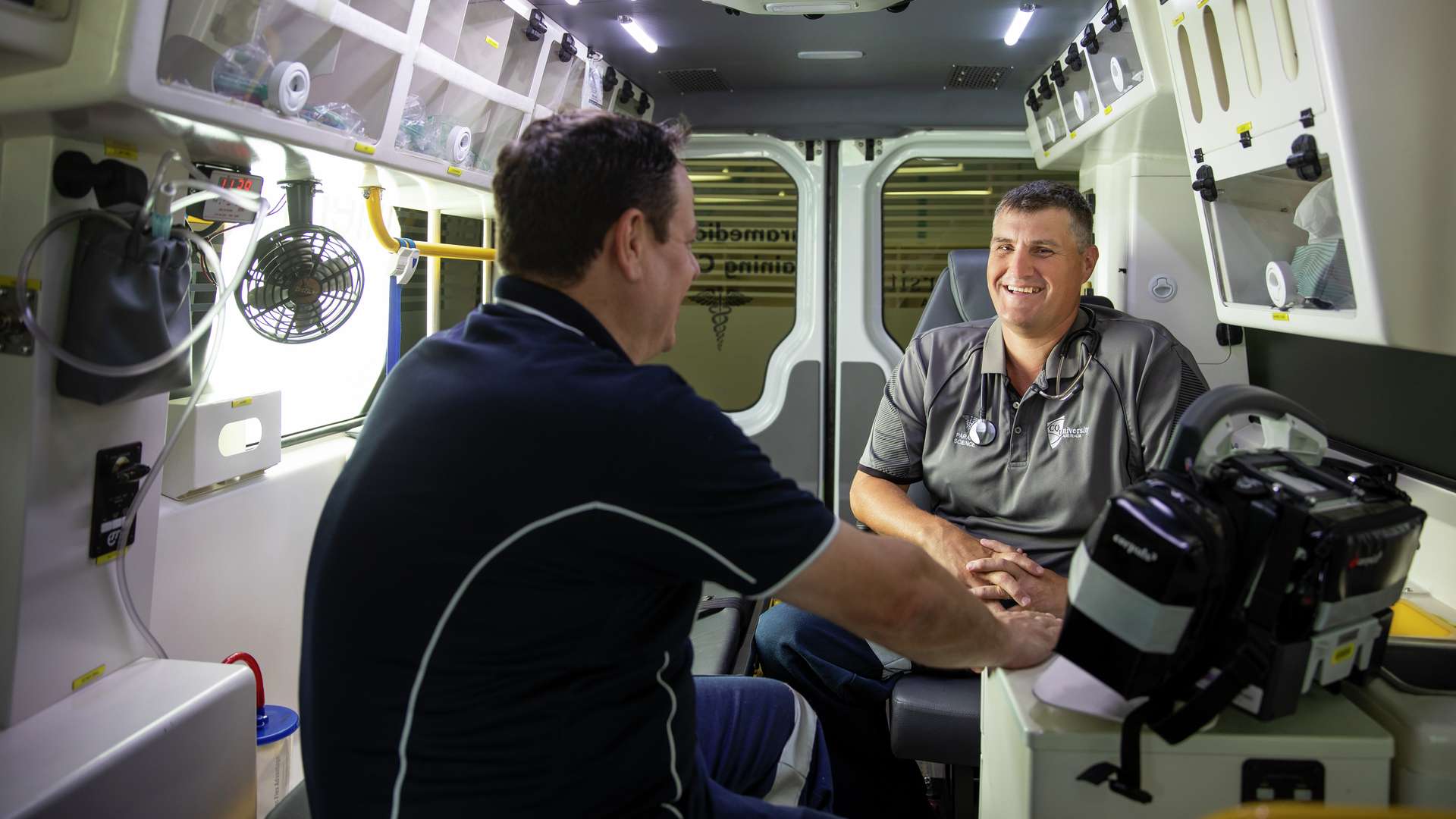 A paramedic student with their teacher inside an ambulance