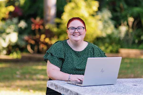Monique Geiszler looking away sitting down with a laptop