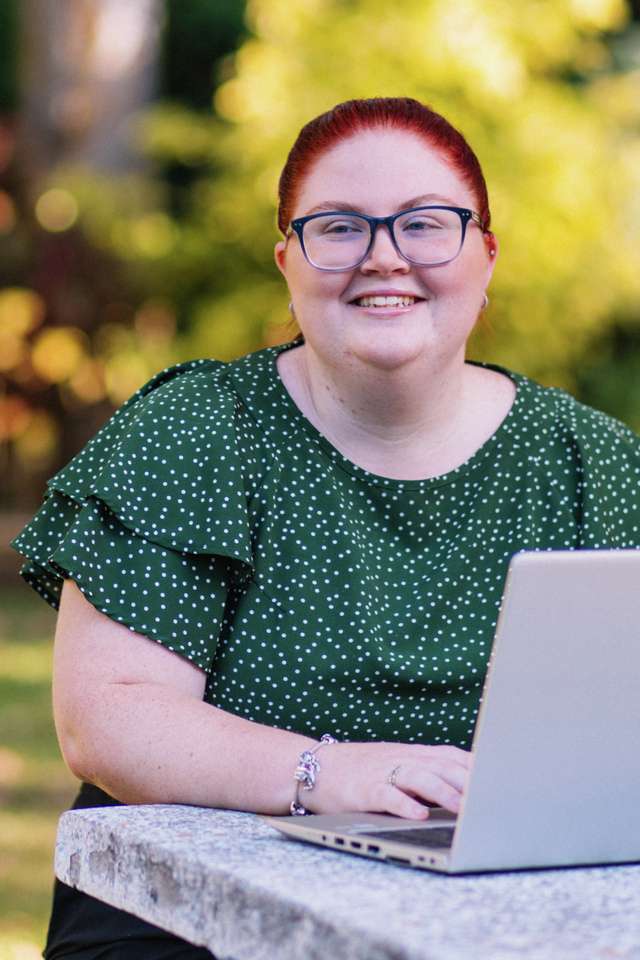 Monique Geiszler looking away sitting down with a laptop