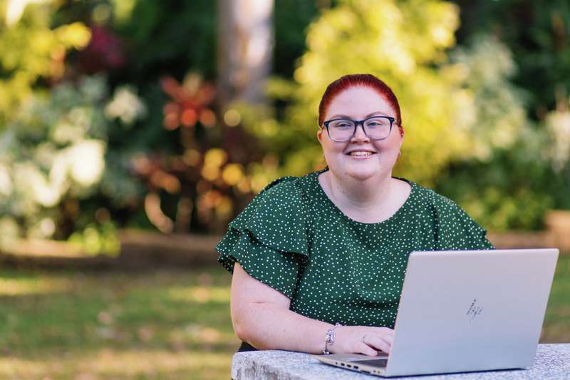 Monique Geiszler looking away sitting down with a laptop