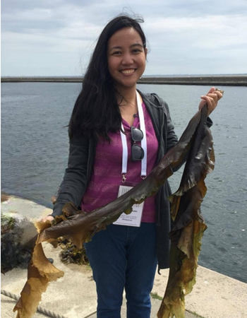 Najeen Arabelle Rula holding seaweed with the ocean in the background