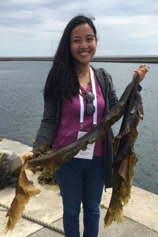 Najeen Arabelle Rula holding seaweed with the ocean in the background
