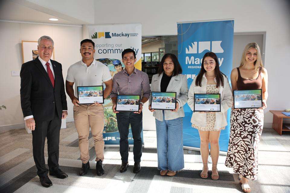 Man in suit standing with five students holding certificates