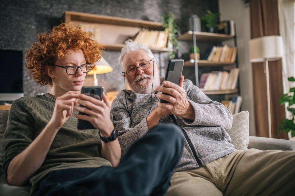 Young man and older man looking at phones