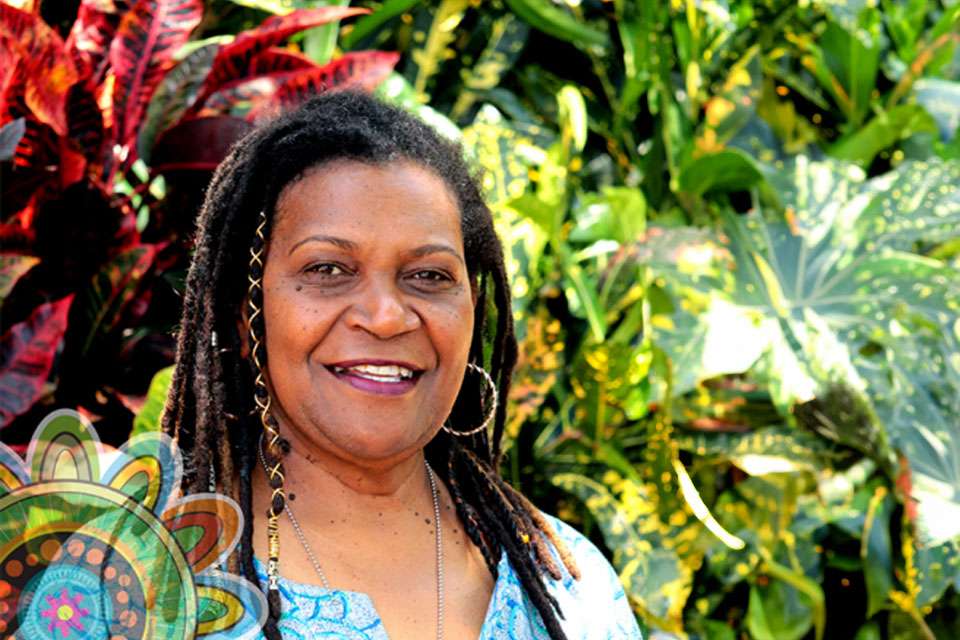 Woman with braids standing in front of foliage