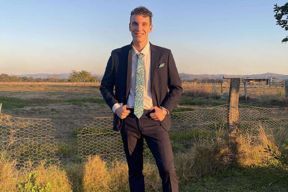 Malachai Clements in a suit with rural landscape