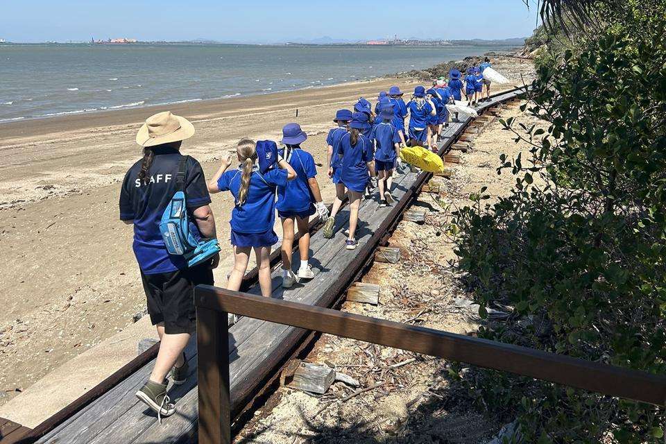 Group of students in blue uniforms walking along beach