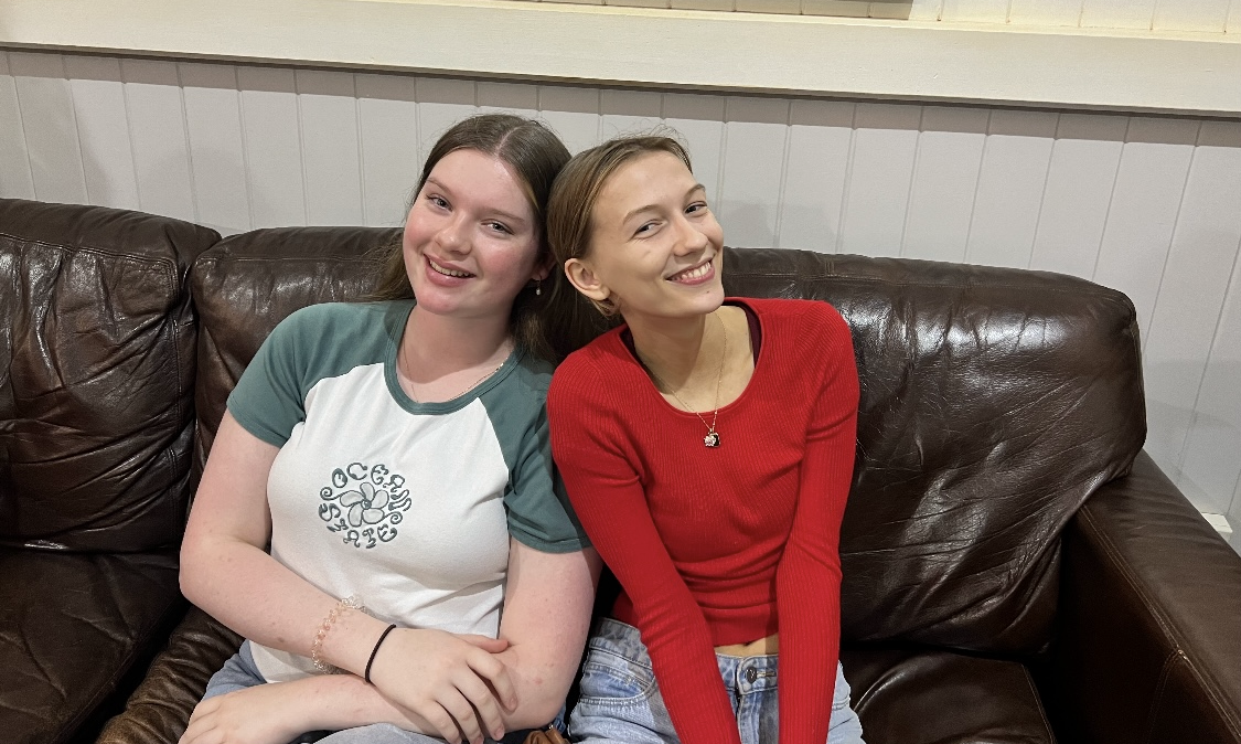 Two young women sitting on a lounge