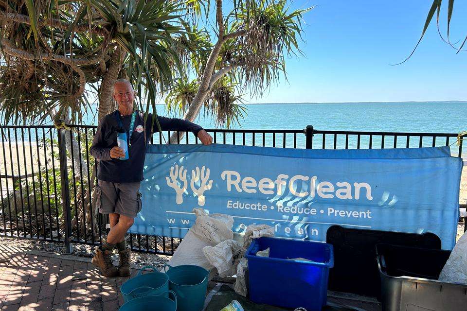 Man standing in front of blue sign with debris