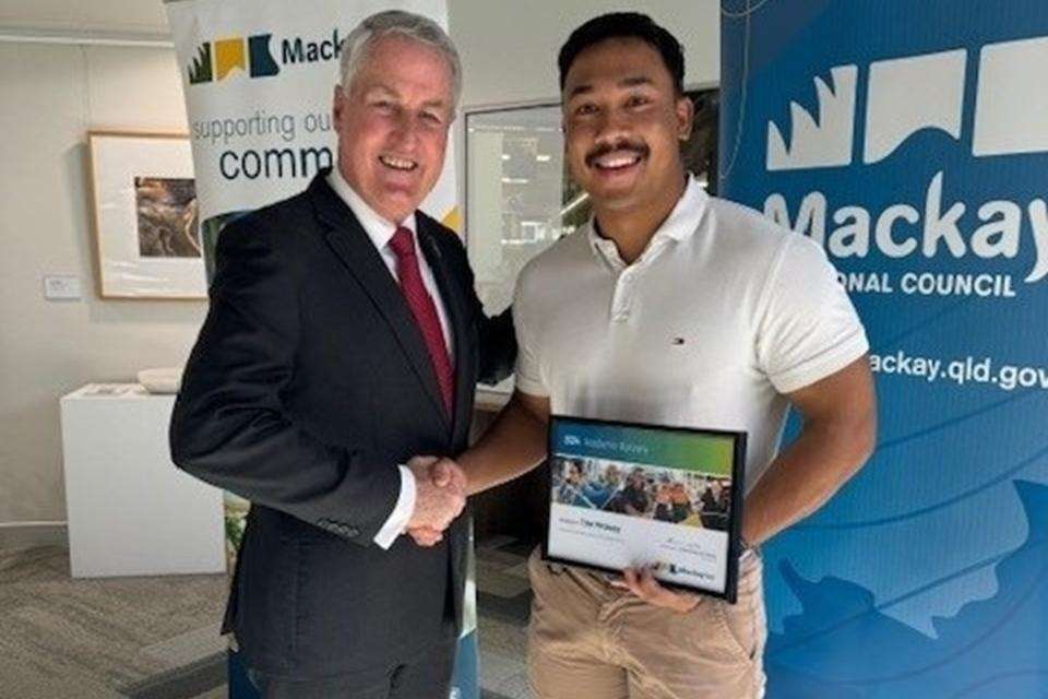 Man in suit shaking hand and awarding certificate to student