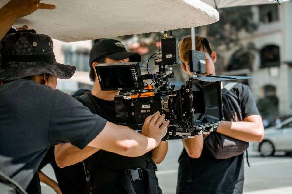 Three men looking in large movie camera