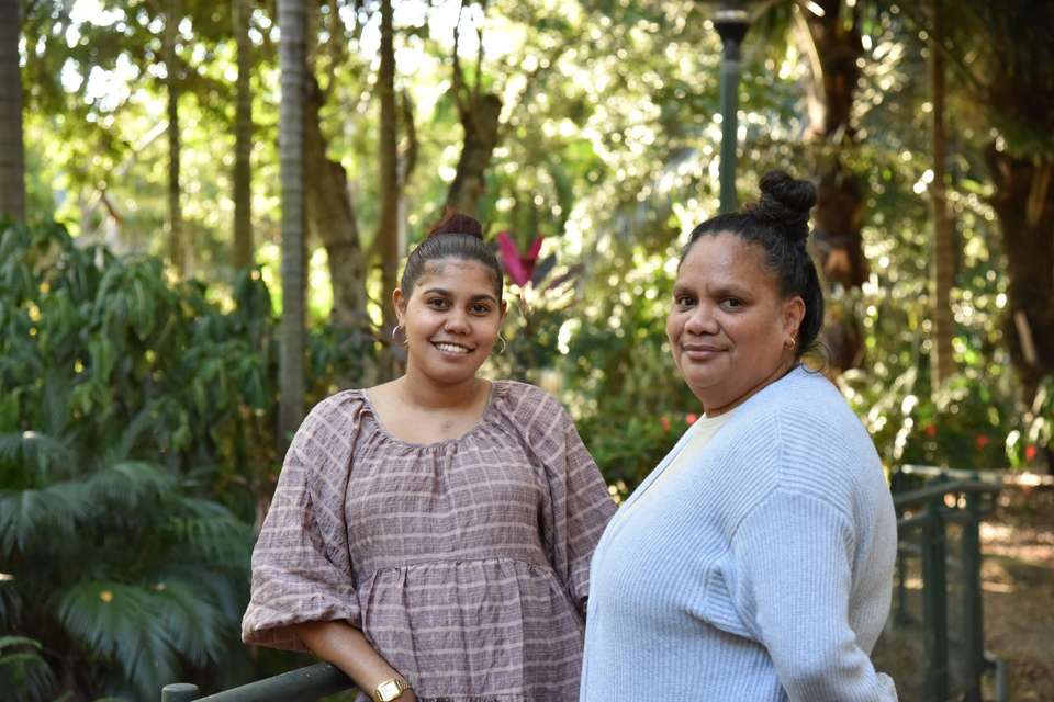 Two women smiling at the camera in an outdoor setting