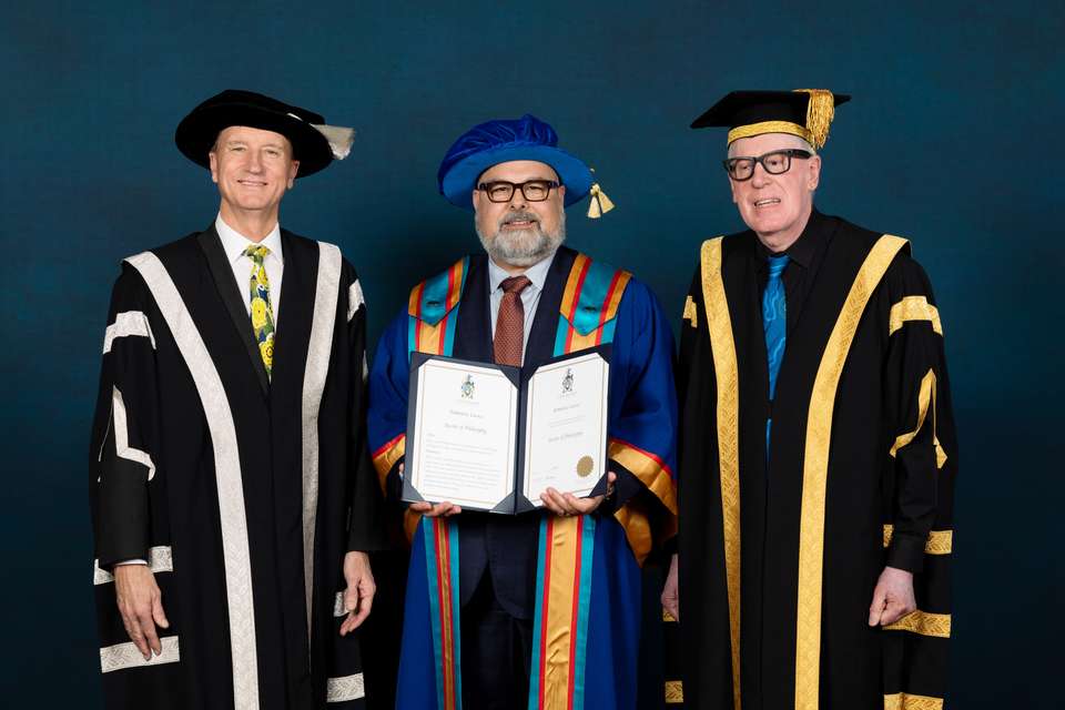 Three men standing in university regalia