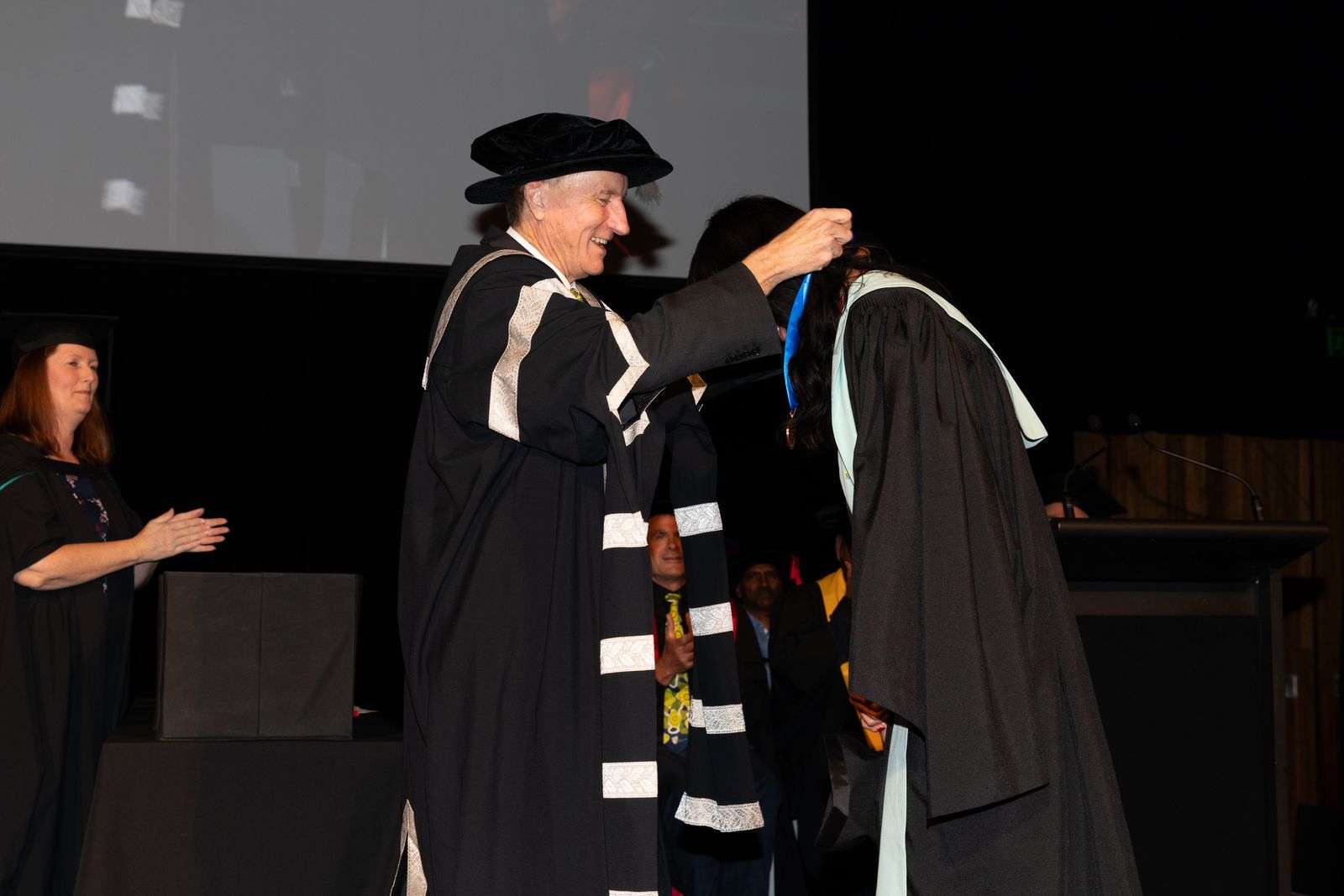 Man placing a medal on a person neck