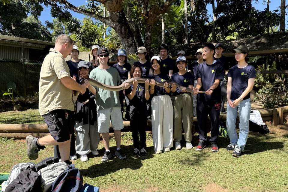 Students holding a large snake