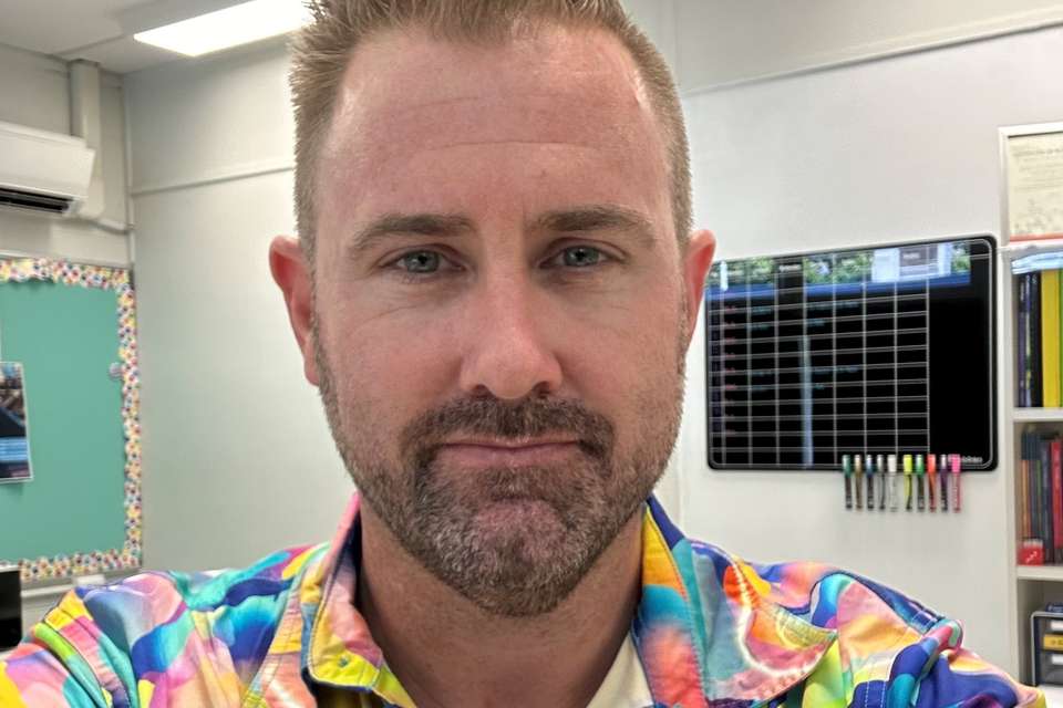 Man in coloured shirt smiling at camera