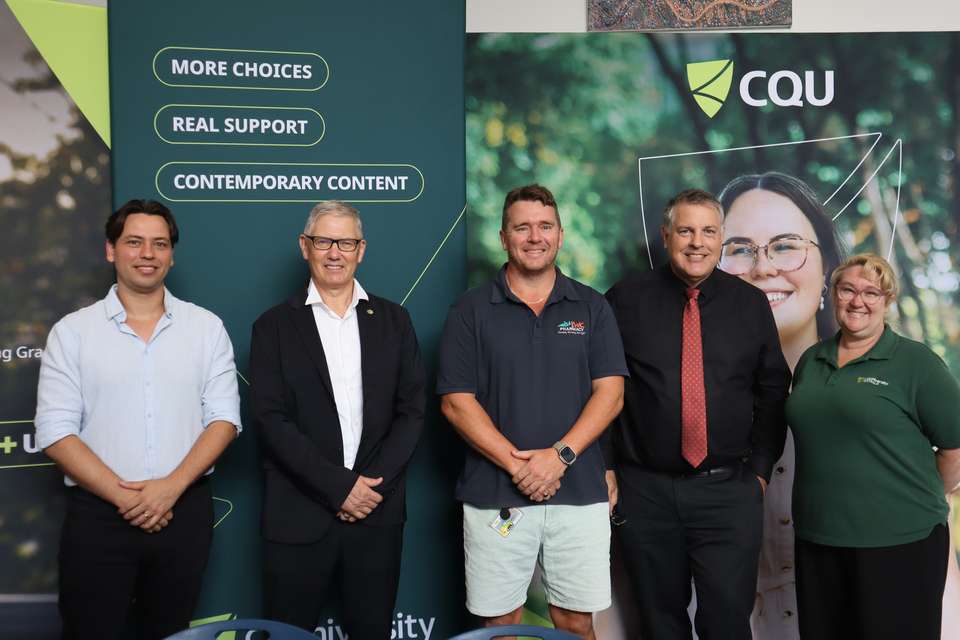Line of people standing in front of CQU banner