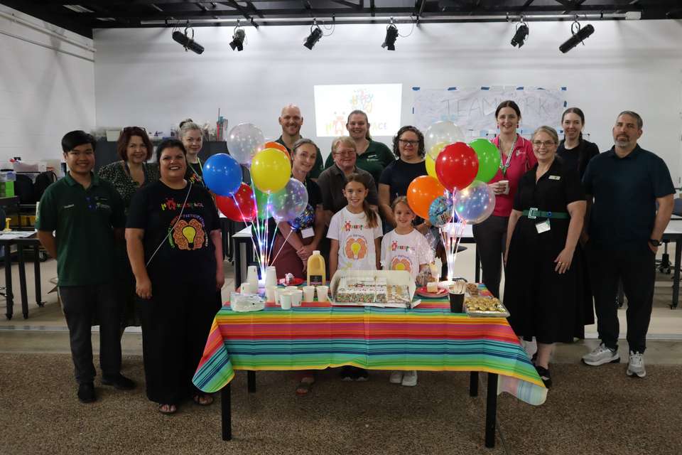 Group of people standing with cake and balloons