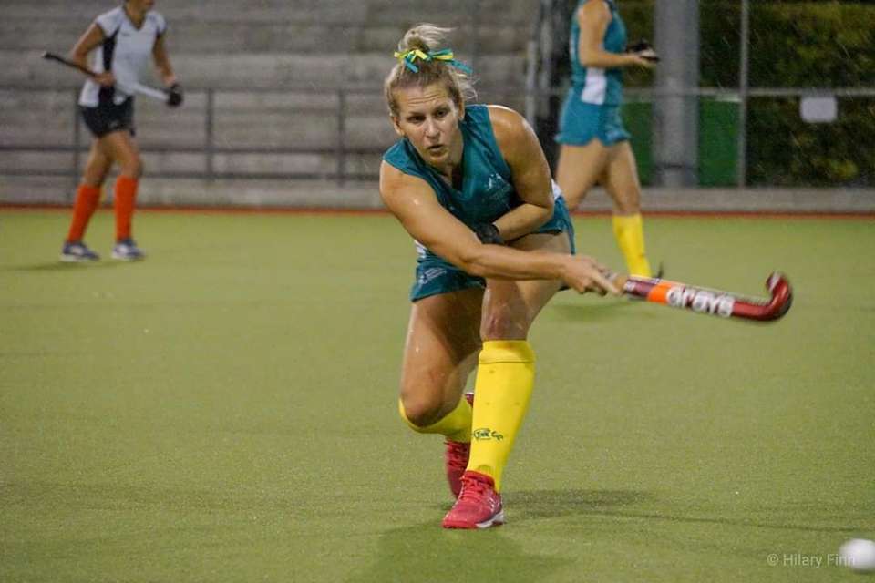 Woman in green and gold playing hockey