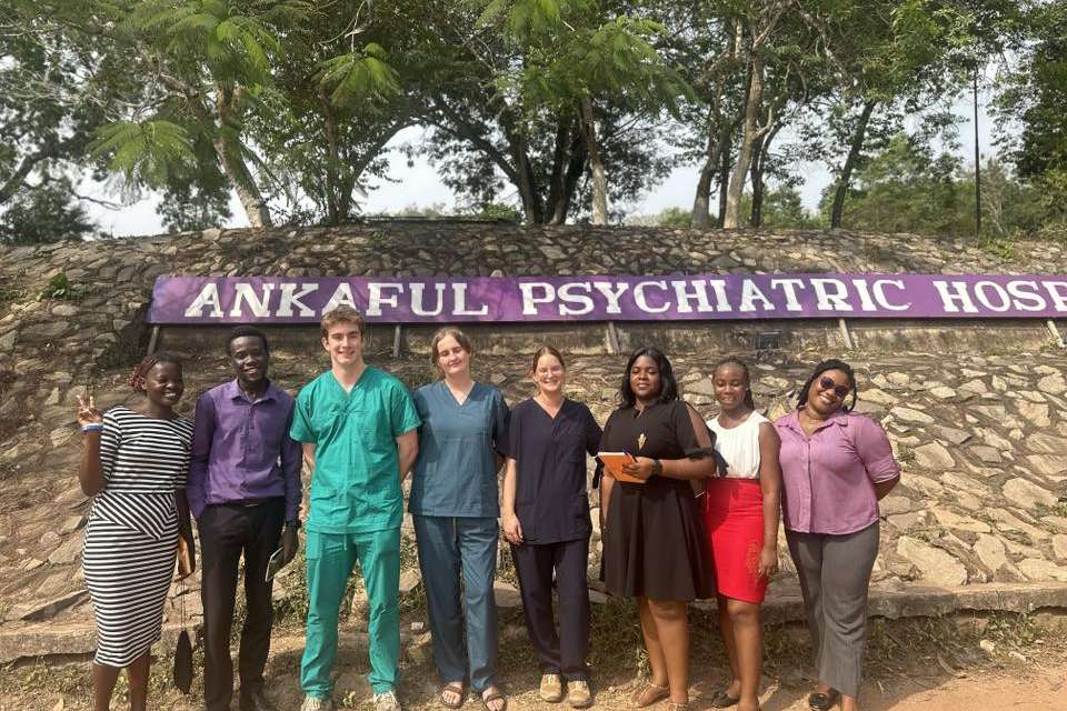 Group of people standing in front of a purple sign.