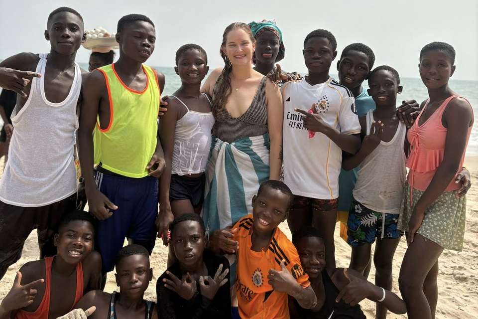 Woman standing on a beach with a group of African children.