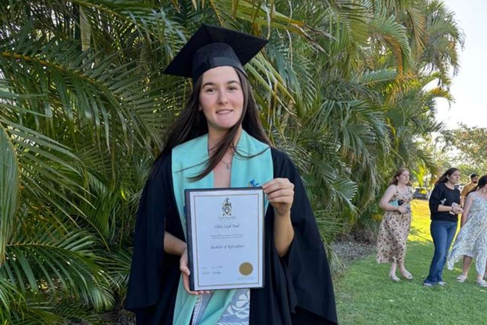 Woman in regalia holding testamur