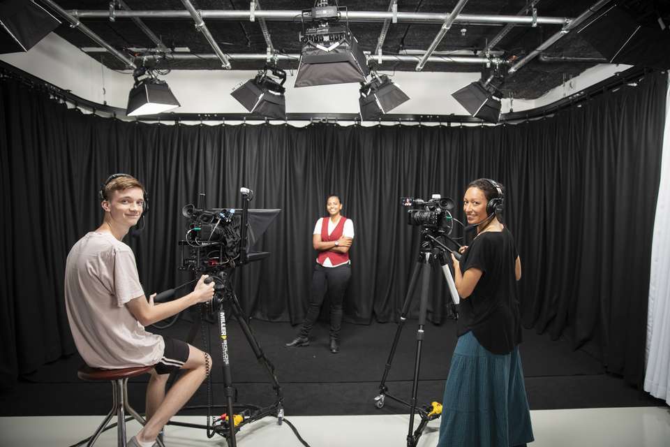 Two digital media students preparing to film someone in a studio.
