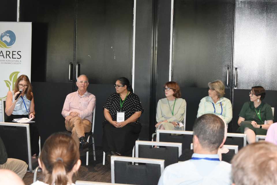 Image of Prof John Rolfe seated with some women on a panel in a large room