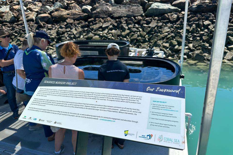 Seagrass nursery project sign with people and water in the background