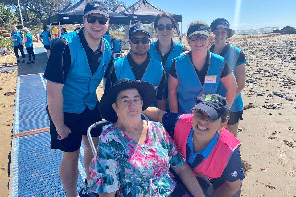 CQU Physiotherapy students and staff smiling at the camera with an elderly woman in her beach wheelchair.jpg