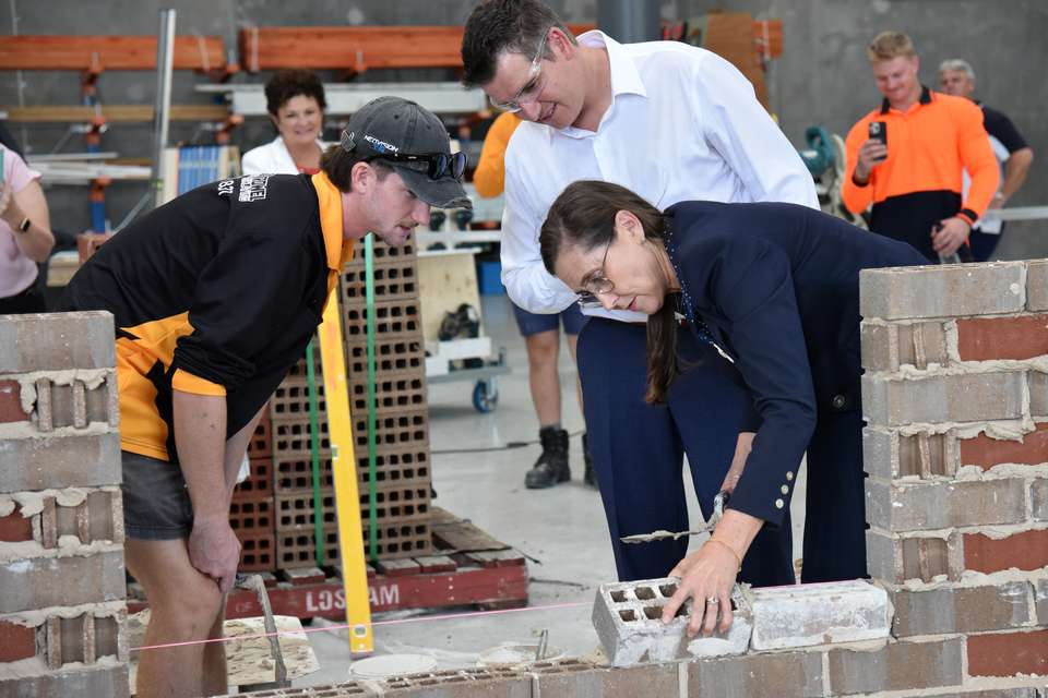 Donna Kirkland lays a brick while an apprentice and Nigel Hutton oversee.JPG