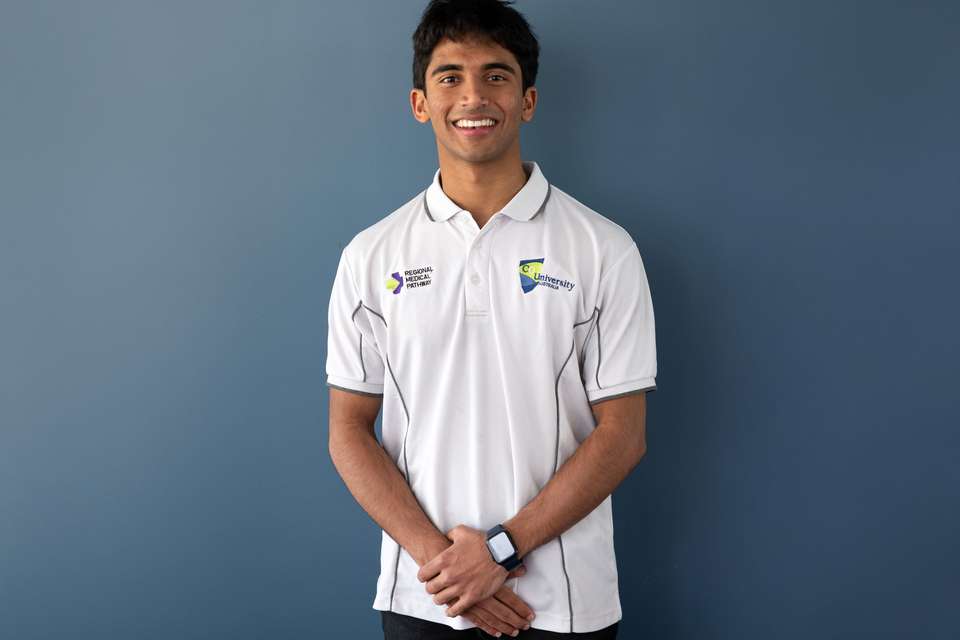 Chamika looks at the camera smiling and wears a white RMP polo shirt.