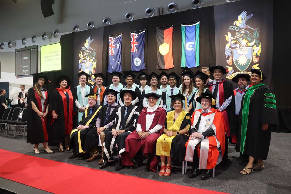 Chamika is pictured in the centre of a large group of graduates and academics on stage after the Bundaberg graduation ceremony. All are wearing academic regalia.