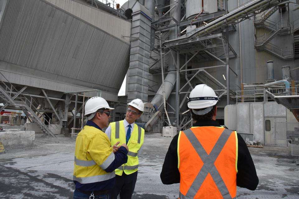 Professor Nick Klomp and staff of QMAG standing in high-vis clothing at the Queensland Magnesia plant