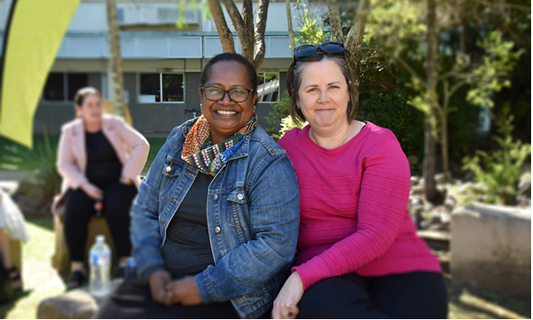 Danessa and Barb sit together at the CQU Rockhampton North campus Yarning Circle. Danessa wears a denim jacket and Barb wears a pink jumper.