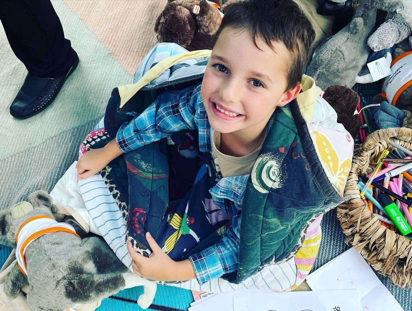 Local Gladstone student Edgar Peacock smiles at the camera surrounded by wildlife toys, pens and paper for illustrating books