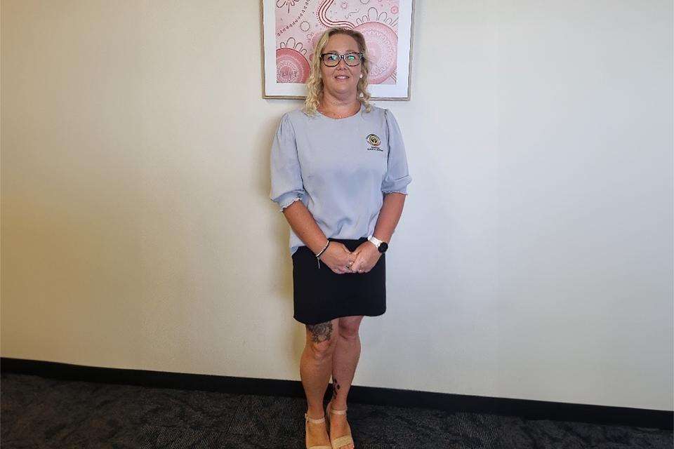 Natasha Hutton standing in front of some Indigenous artwork smiling at the camera