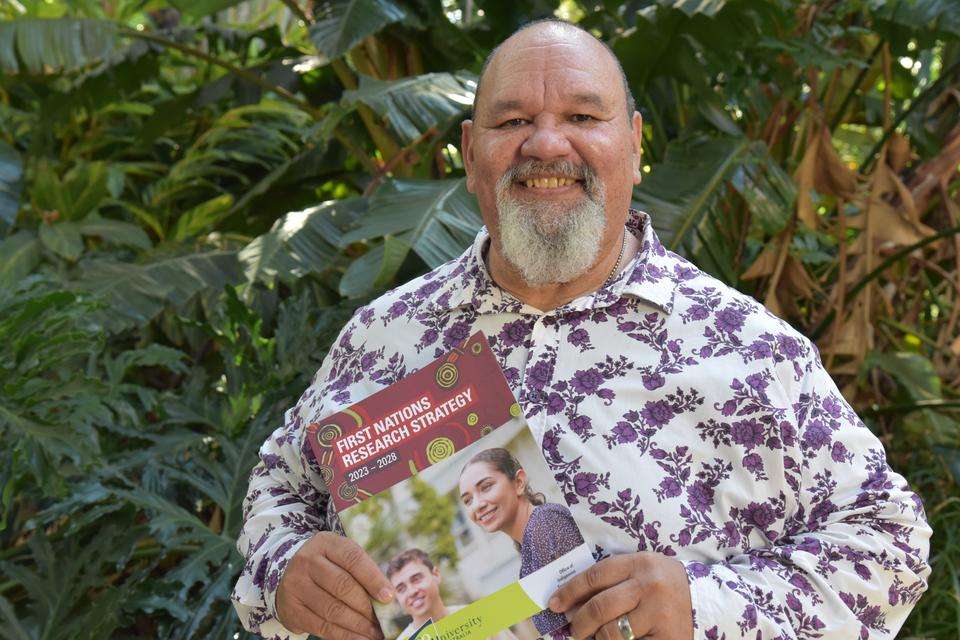 Professor Adrian Miller holding a copy of the First Nations Research Strategy document