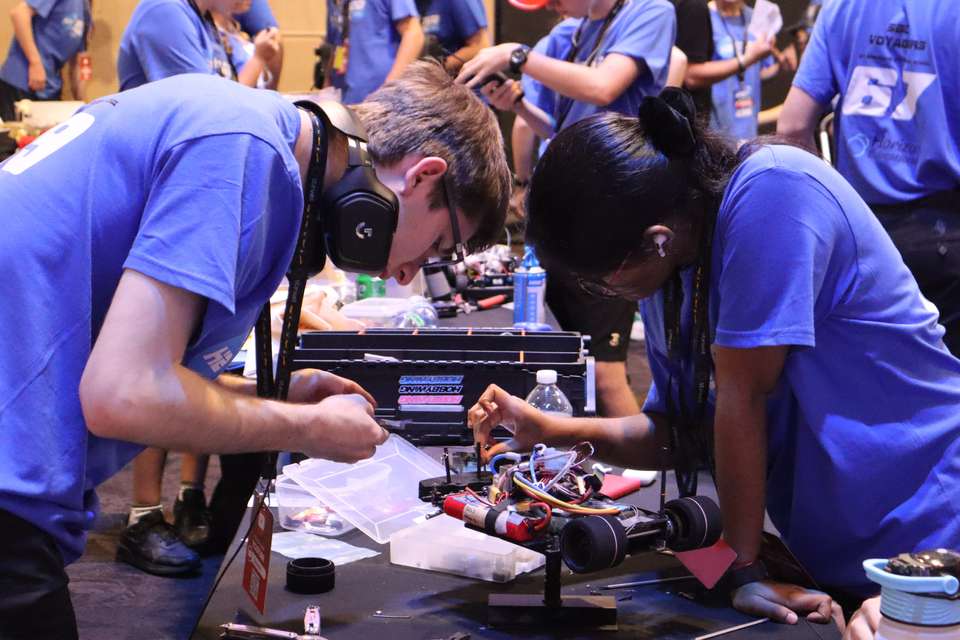 Two high school students and Hydrogen Grand Prix competitors work on a stripped-back vehicle for maintenance