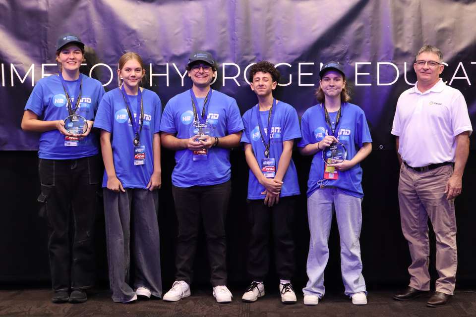 Hydrogen Grand Prix first-place winners stand with their medals and trophies with a stakeholder/sponsor from Stanwell