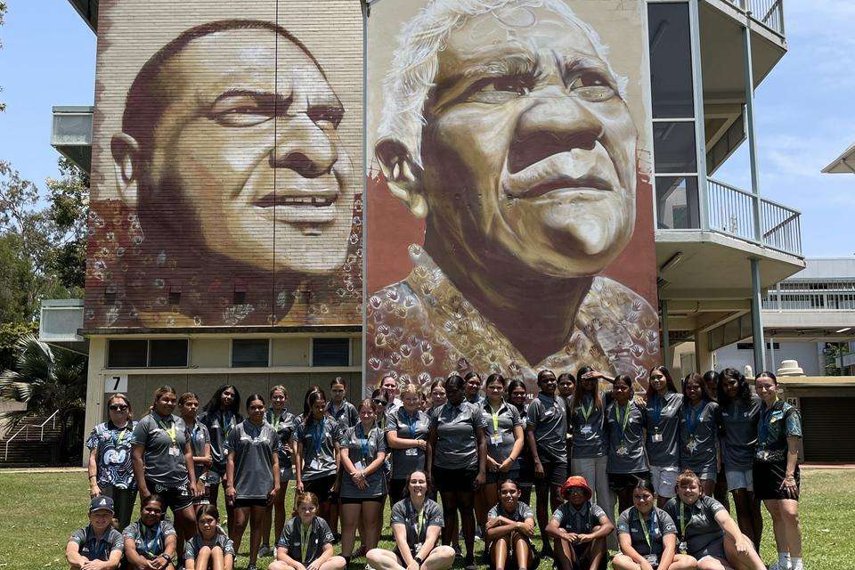 The Indigenous Girls Academy Camp group in front of a large mural