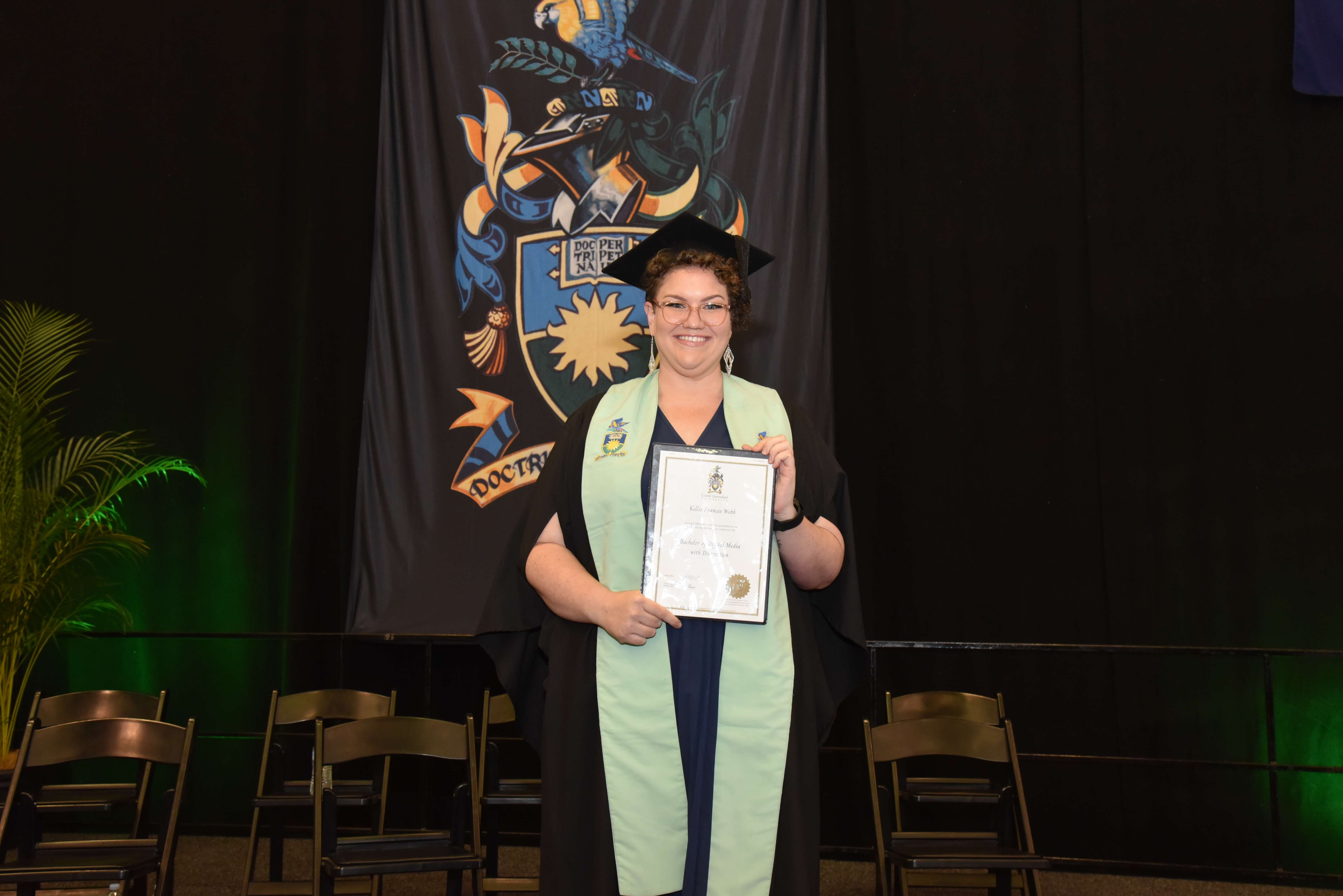 Kellie Webb holding her degree at a CQUniversity graduation ceremony