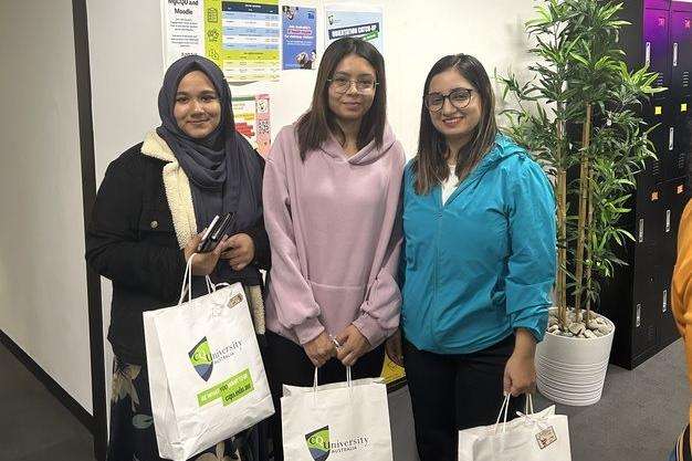 Three students hold their Campus Kindness food packs.