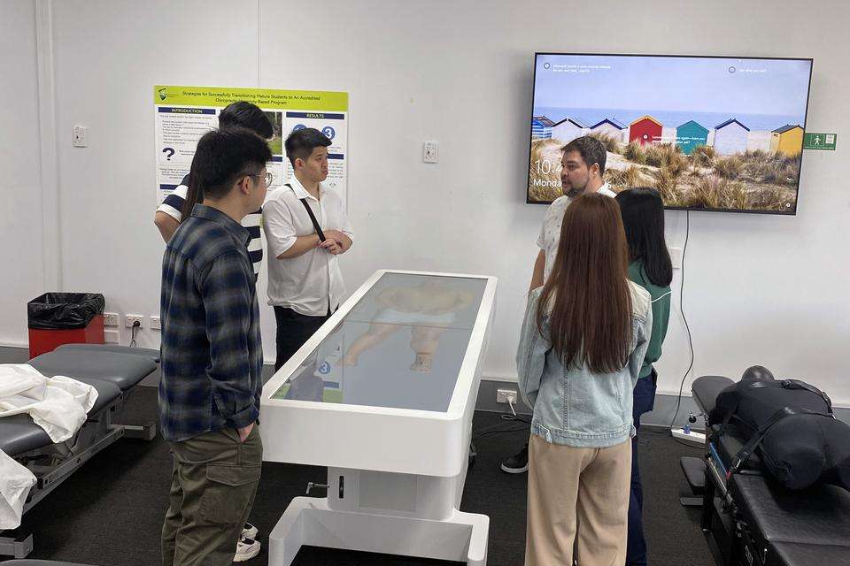 A group of men and women standing next to a digital display table