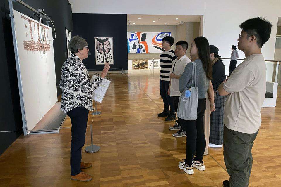 A group of men and women in a art musem admiring some artwork