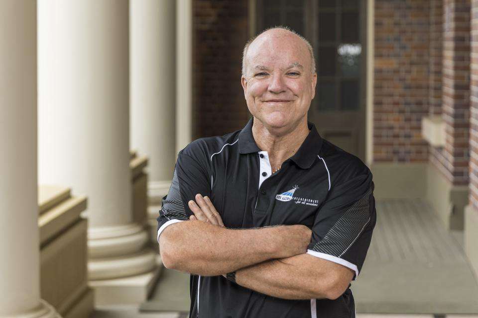Tony George stands, smiling, on the front verandah of a heritage building.
