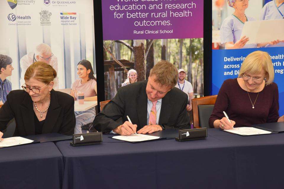 Stakeholders of CQU, UQ and CQHHS sign memorandums of understanding, against a backdrop of respective media banners