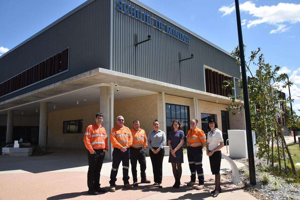 A group of seven people, some in high-vis uniforms and three women in corporate clothing standing outside the School of Mining building