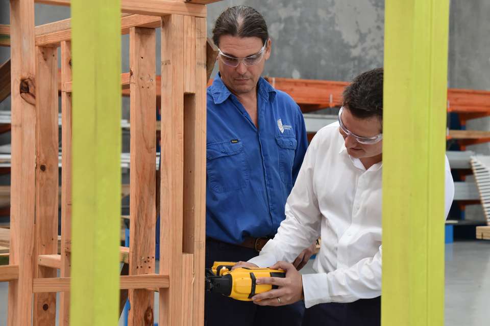 Nigel Hutton uses a nail gun on timber framing while being overseen by cqu staffer.JPG